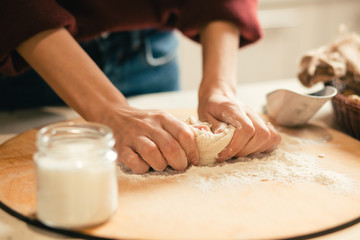 Obraz na płótnie Canvas Hands of woman kneading dough on the wooden board