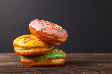 Three colorful donuts on a wooden table, on a black background. Bakery menu design concept. Hanukkah background.