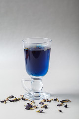 Pour the milk into a Cup of blue butterfly pea tea Anchan on a gray background. Blue Thai tea and milk mixed