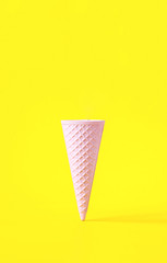 Wafer ice cream cone  light pink colors on yellow background. Minimalistic concept. Idea...