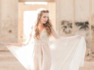 Portrait of a young bride in white lace boudoir with wavy dark hair
