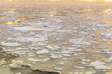 Cracked ice on the river. Spring warming, melting ice. Evening time