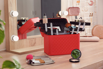Beautician case with professional makeup products and tools on wooden dressing table