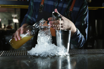 Barman making tropical cocktail at counter in pub, closeup