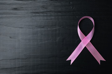 Pink ribbon on wooden background, top view with space for text. Breast cancer concept