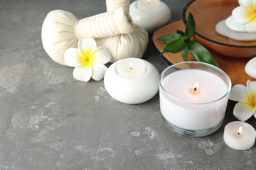Beautiful spa composition with candles and flowers on grey background, space for text