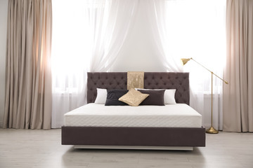 Comfortable bed with new mattress near window in room. Healthy sleep