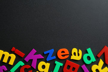 Plastic magnetic letters on black background, top view with space for text