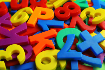 Colorful plastic magnetic letters and numbers as background, closeup