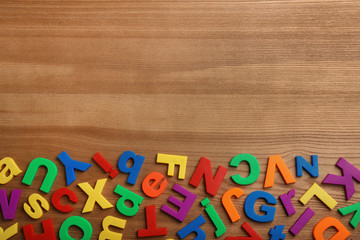 Plastic magnetic letters on wooden background, top view with space for text
