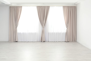 Windows with elegant curtains in empty room