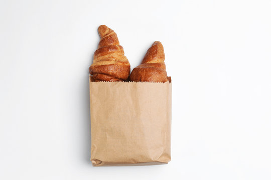 Paper bag with croissants on white background, top view. Space for design