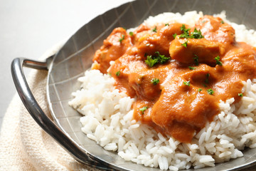 Delicious butter chicken with rice in dish and napkin on table
