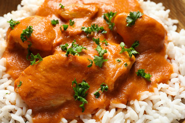 Delicious butter chicken with rice as background, closeup
