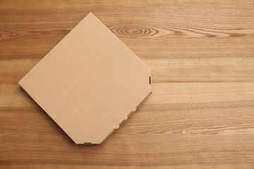Cardboard pizza box on wooden background, top view. Mockup for design