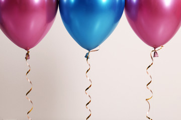 Color balloons with ribbons on white background, closeup. Space for text
