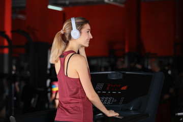 Fototapeta na wymiar Young woman listening to music with headphones at gym