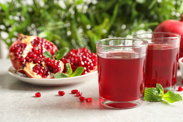 Composition with glasses of fresh pomegranate juice on table. Space for text