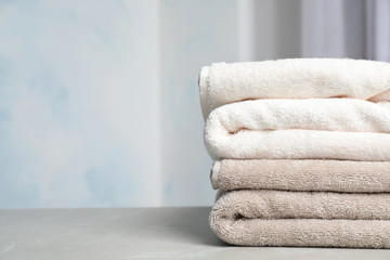 Stack of soft bath towels on table against blurred background. Space for text