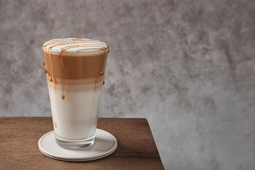 Glass of tasty caramel macchiato on table, Space for text