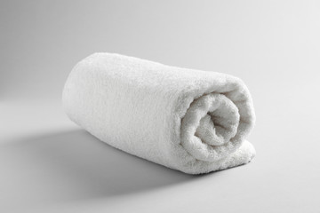 Fototapeta na wymiar Fresh soft rolled towel on light background