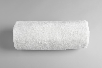 Fresh soft rolled towel on light background, top view