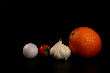Collection of different vegetables garlic , sweet paprika and orange fruit  on black background