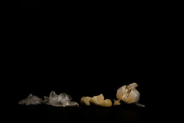 closeup peeled garlic with small pieces on a black background with a free copy