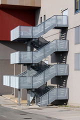 Outdoor metal staircase secured with metal mesh protection mounted on side of industrial building...