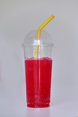 Red soda water in plastic cup with yellow straw isolated on white background. Close up of and selective focused.