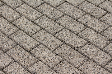 Stone tiles outdoor background texture with small black sand on top on warm sunny day