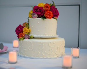 Beautiful white wedding cake with real flowers surrounded by candles