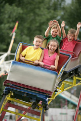 Children on a roller coaster at a county fair, amusement park, or carnival.