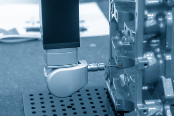 The  multi axis CMM machine measure the aluminum automotive part in the light blue scene.The automotive part quality control concept.