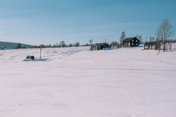 Village in the winter. Houses in Siberia under the snow. Buildings in the snow. Countryside in winter.
