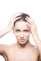 Naklejka premium Beautiful face of young caucasian brunette woman with natural lips, make-up and blue eyes isolated on white. Touch her perfect skin. Studio portrait