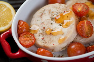 Close-up of hake medallions baked with cherry tomatoes, selective focus, horizontal shot