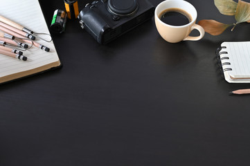 Creative workplace camera, coffee and note paper on black table with selective focus.