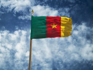 Cameroon flag Silk waving flag of Cameroon made transparent fabric with wooden flagpole gold spear on background sunny blue sky white smoke clouds real retro photo Countries of world 3d illustration