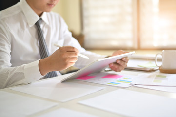 Closeup businessman analysis data in digital tablet on office desk.