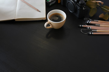Creative workplace camera, coffee and note paper on black table with selective focus.