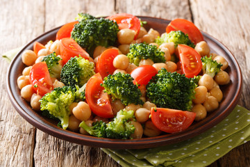Fitness balanced salad of broccoli, chickpeas and fresh tomatoes with olive oil close-up on a plate. horizontal