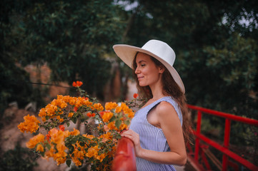 girl in a hat and dress next to yellow flowers