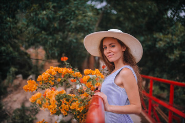 Fototapeta na wymiar girl in a hat and dress next to yellow flowers