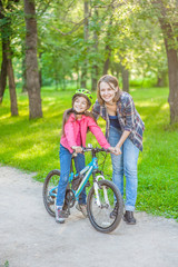 mother and daughter ride bikes in the forest