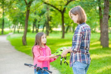 Mom gives his daughter a helmet for a safe ride on roller skates