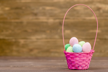 Easter basket filled with colorful eggs on wooden background. Empty space foe text