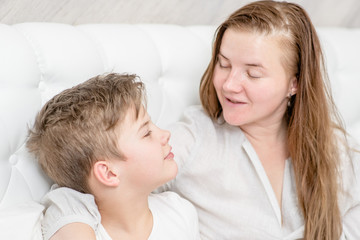 Young boy talking with his young mother at bedroom before bedtime