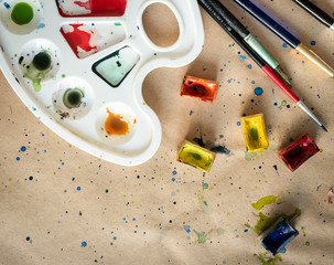 Art palette with brushes and paint boxes on workshop table