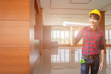 Engineer checking in decorate Interior room completed with hand holding rolled blueprints and wear yellow helmet. concept construction background